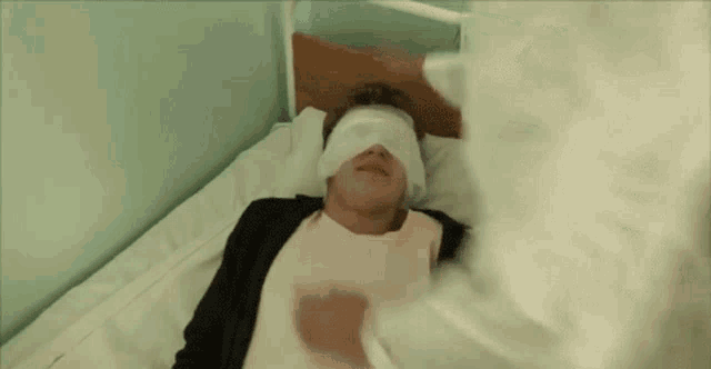 a man is laying in a hospital bed with a bandage on his head .