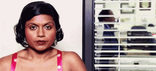 a woman is standing in front of a window with blinds on it .