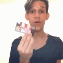 a young man is holding a credit card in front of his mouth .