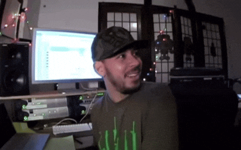 a man wearing a hat and a shirt that says ' bamboo ' is smiling in front of a computer