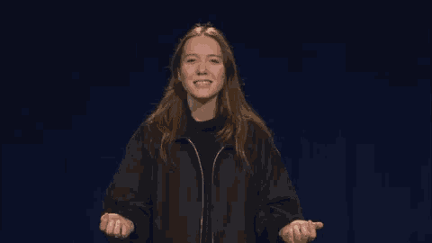 a woman in a black jacket is smiling and making a funny face