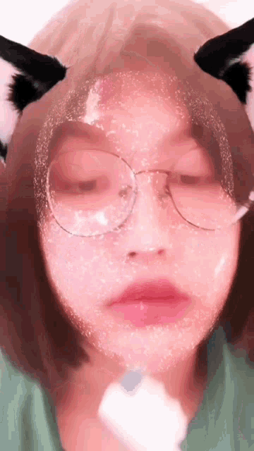a girl wearing glasses and cat ears has a pink filter on her face