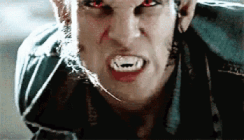 a close up of a vampire with red eyes and teeth .