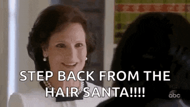 a woman is smiling and talking to another woman and says `` step back from the hair santa !!! ''