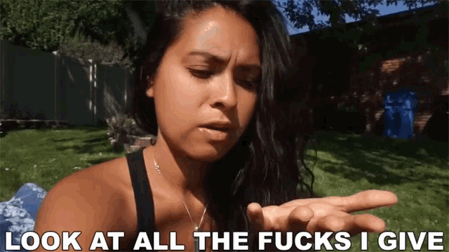 a woman is laying in the grass with the words look at all the fucks i give