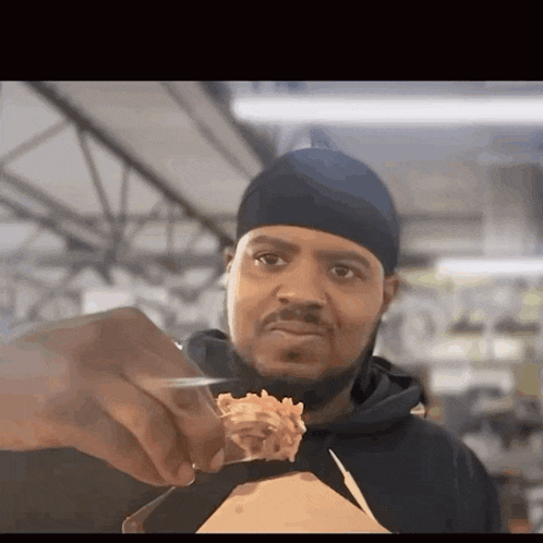 a man in a black beanie is holding a piece of food