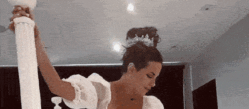 a woman in a white dress is holding a white pillar