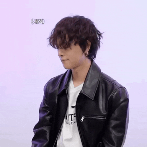 a young man wearing a black leather jacket and a white t-shirt that says tf on it