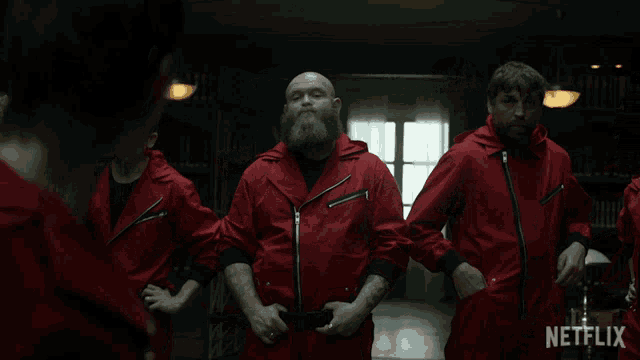 a group of men in red jumpsuits are standing in a dark room with a netflix logo in the corner