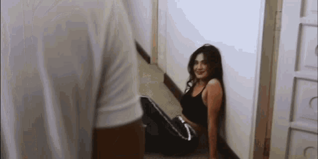 a woman is sitting on the floor leaning against a wall in a hallway .