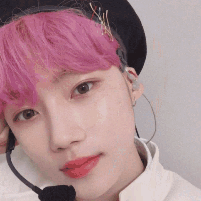 a young man with pink hair is wearing a headset
