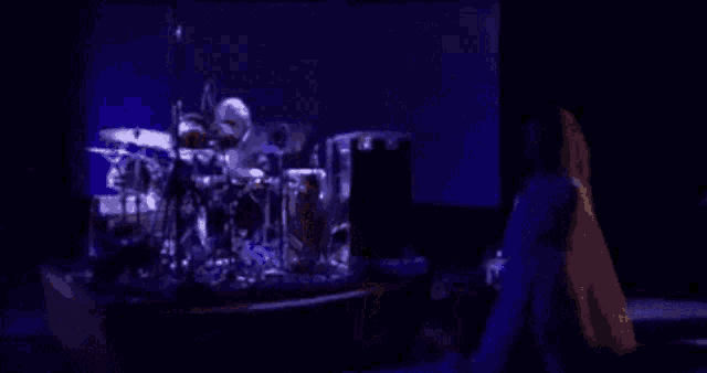 a blurry picture of a person playing drums in front of a screen