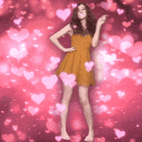 a woman in a yellow dress stands in front of a pink background with hearts