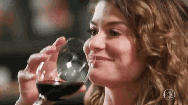 a woman drinking a glass of wine with the letter o on the bottom right