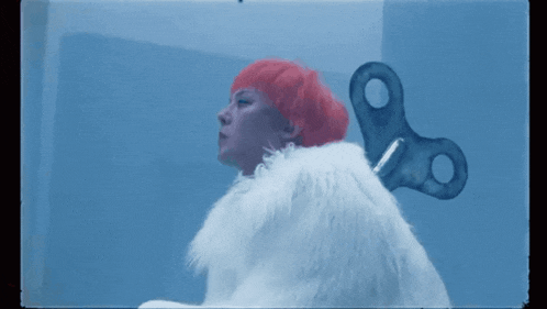 a woman with red hair is holding a wind up key