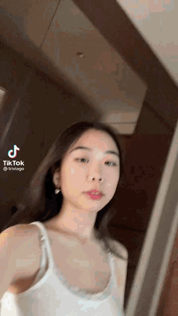 a woman in a white tank top has a tiktok icon on her face