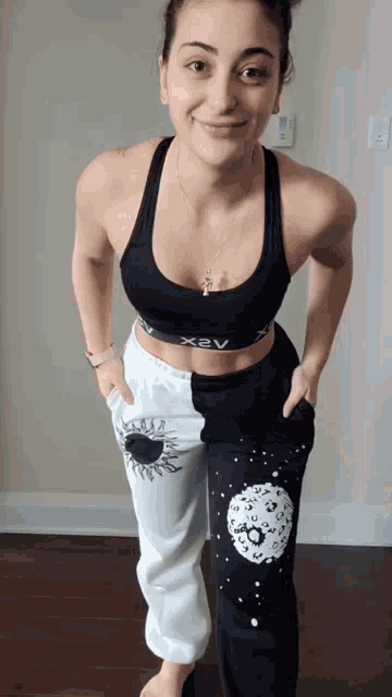 a woman wearing a black x2v bra and white sweatpants