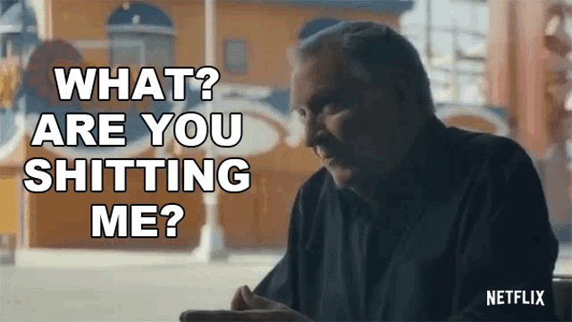 a man sitting at a table with the words " what are you shitting me " written above him