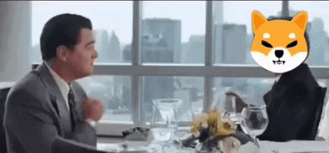 a man in a suit and tie is sitting at a table with a shiba inu on his head .