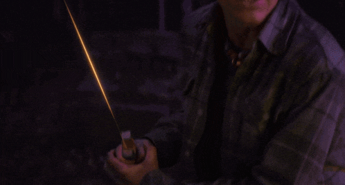 a young boy in a plaid shirt is holding a glowing object in his hand .