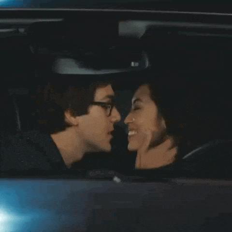a man and woman are kissing in a car .
