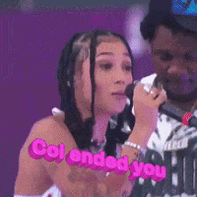 a woman is singing into a microphone while a man looks on and says colended you .