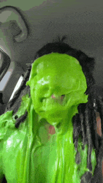 a person with green slime on their face and dreadlocks