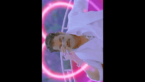 a man with a mustache and glasses is standing in front of a purple circle .