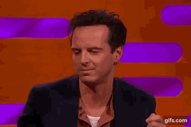 a man in a suit is making a funny face on a purple background .