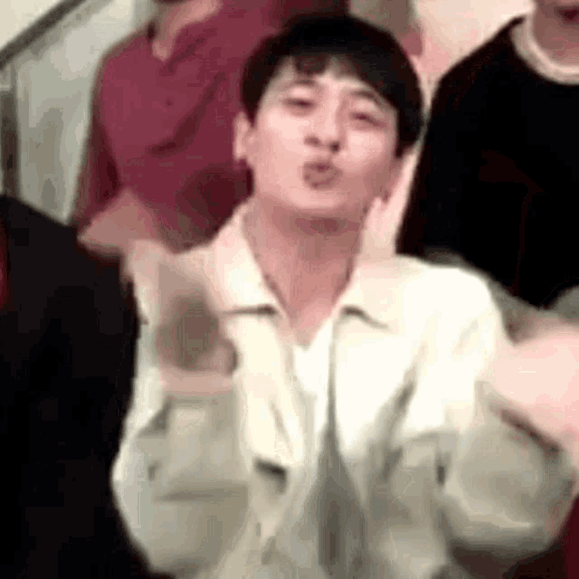 a man is blowing a kiss in front of a crowd of people .