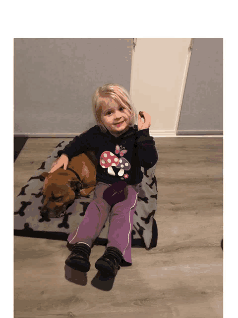 a little girl sitting next to a dog wearing a shirt that says mushrooms