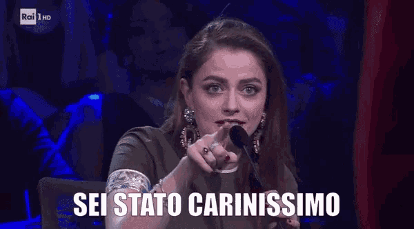 a woman speaking into a microphone with the words sei stato carinissimo behind her