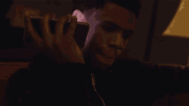 a man talking on a cell phone with a lamp in the background