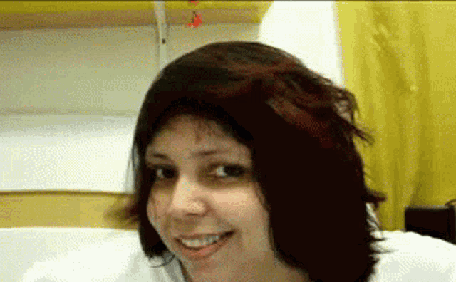 a woman with short dark hair is smiling and looking at the camera