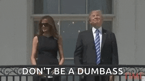 a man in a suit and tie and a woman in a black dress are standing on a balcony .