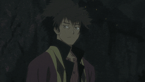 a man with a purple shirt and black collar is smiling in the dark