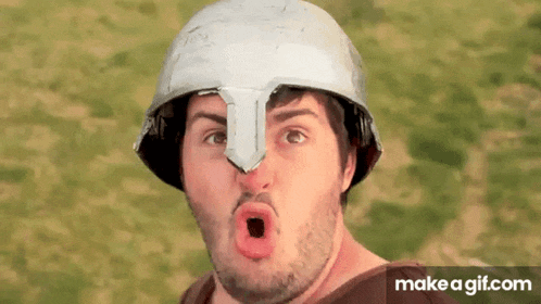 a man wearing a helmet made out of cardboard making a funny face .