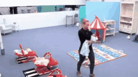 a woman is holding a baby in a room with toys and a tent .