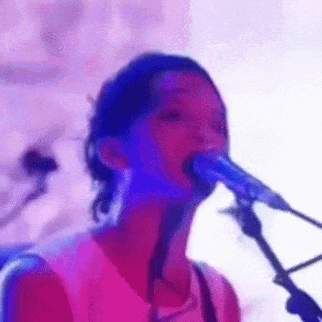 a woman is singing into a microphone on a stage in front of a crowd .
