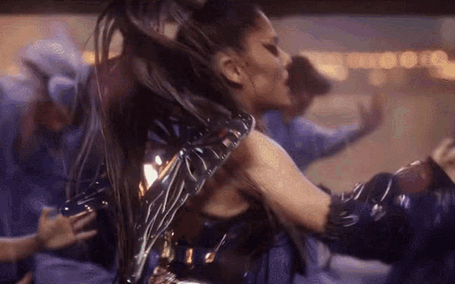 a woman in a futuristic outfit is dancing in front of a crowd .