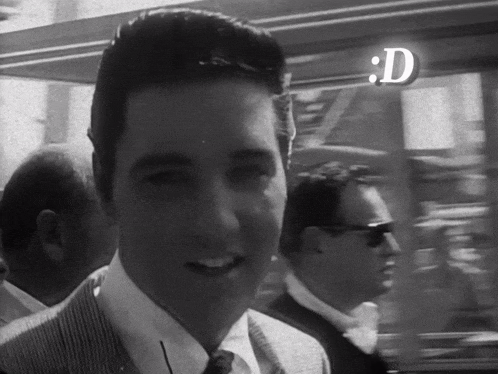 a man in a suit and tie is smiling in a black and white photo