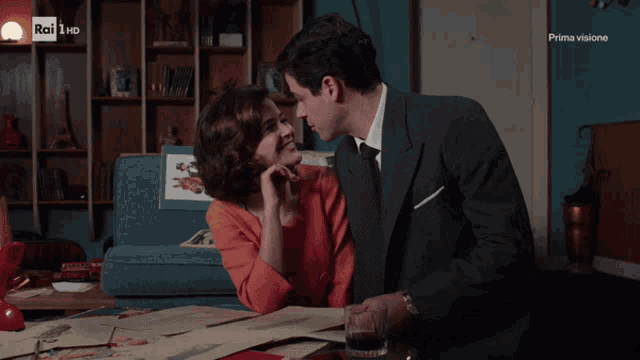 a man and woman are kissing in front of a sign that says rai
