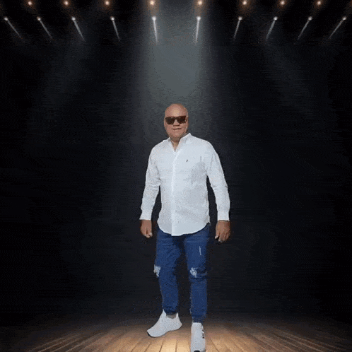 a man wearing sunglasses and a white shirt is dancing on stage