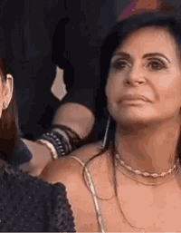 a woman wearing a necklace and earrings is sitting next to a man .