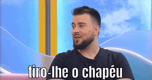 a man with a beard says " tiro-lhe o chapeu " in a foreign language