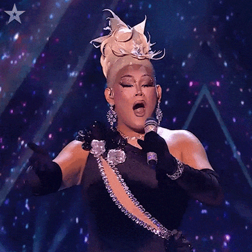 a woman singing into a microphone on a stage with a star behind her