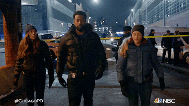 a group of police officers walking down a street with a nbc logo in the corner