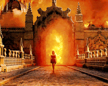 a woman in a red dress is walking through a burning building