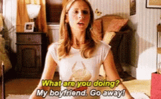 a woman in a white shirt is sitting in a lotus position in a living room and talking to her boyfriend .
