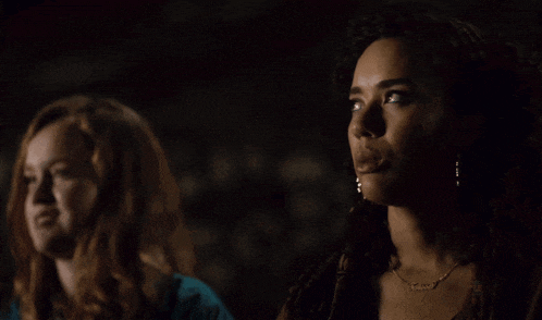 a woman wearing a necklace with the name james on it talks to another woman